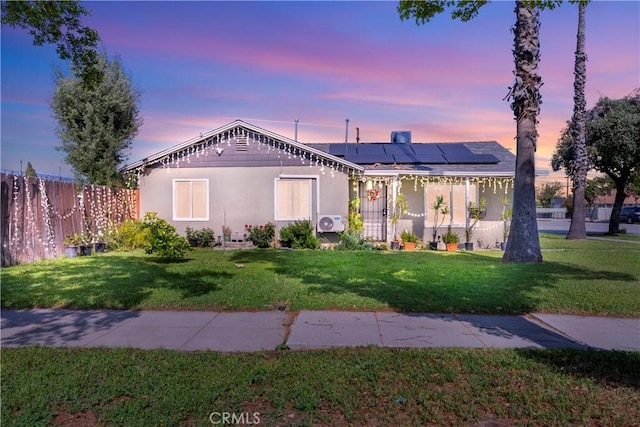 2113 Herrington Ave, San Bernardino, CA 92411 - view of front of home with stucco siding, roof mounted solar panels, fence, and a yard