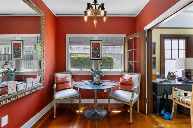 dining area featuring crown molding, wood finished floors, a chandelier, and a wealth of natural light