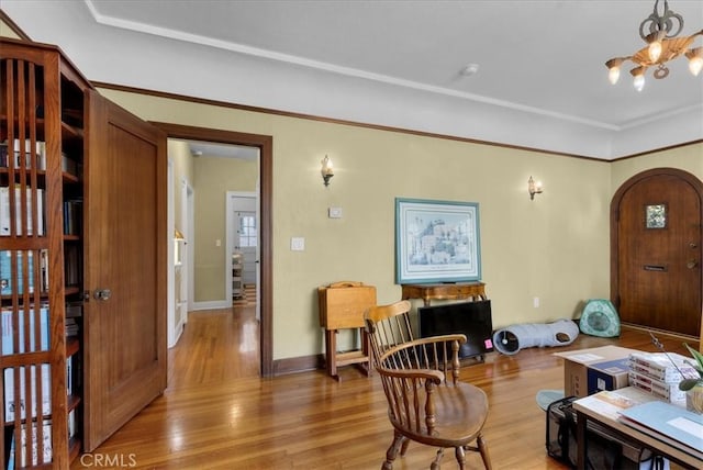 interior space featuring an inviting chandelier, arched walkways, baseboards, and light wood finished floors