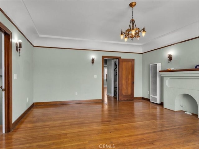 unfurnished living room with baseboards, a heating unit, a notable chandelier, and wood finished floors