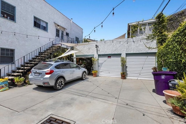exterior space with stairway, a garage, and stucco siding