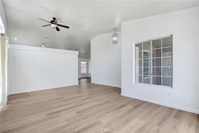 unfurnished living room featuring baseboards, ceiling fan, vaulted ceiling, and wood finished floors