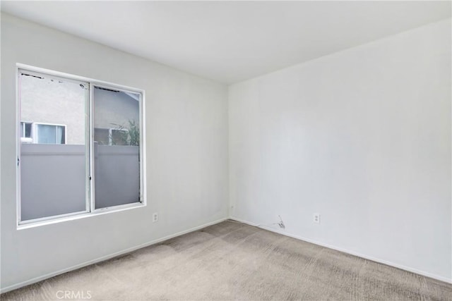 carpeted empty room featuring baseboards