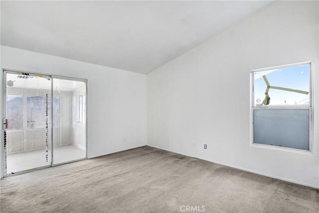 carpeted spare room featuring plenty of natural light and vaulted ceiling