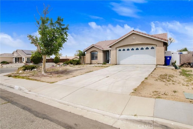 ranch-style house with fence, an attached garage, stucco siding, a tiled roof, and driveway