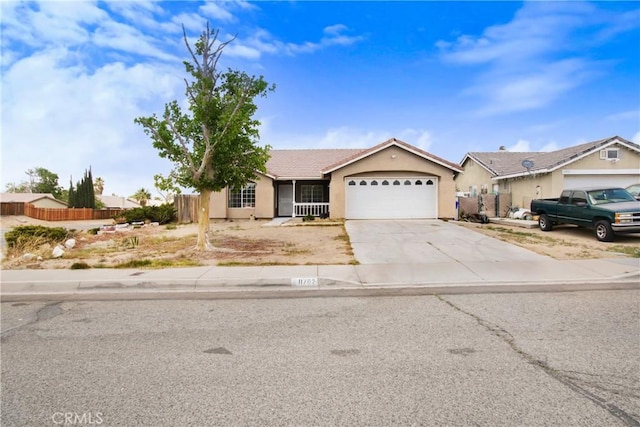 ranch-style home with a garage, fence, stucco siding, a tiled roof, and concrete driveway