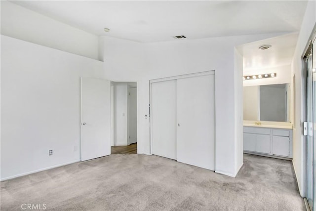 unfurnished bedroom with carpet floors, lofted ceiling, ensuite bath, and visible vents