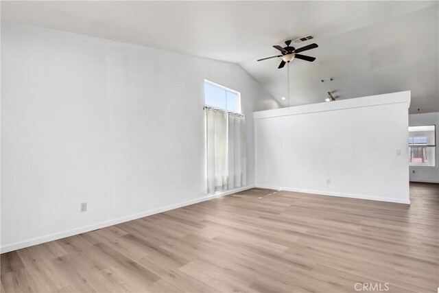 interior space featuring light wood-style floors, baseboards, vaulted ceiling, and a ceiling fan