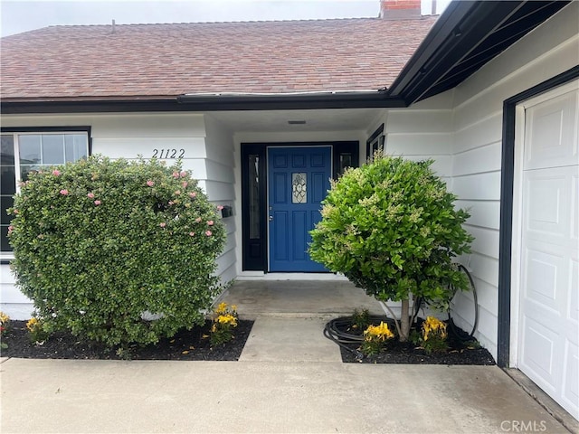 property entrance with a shingled roof and a chimney