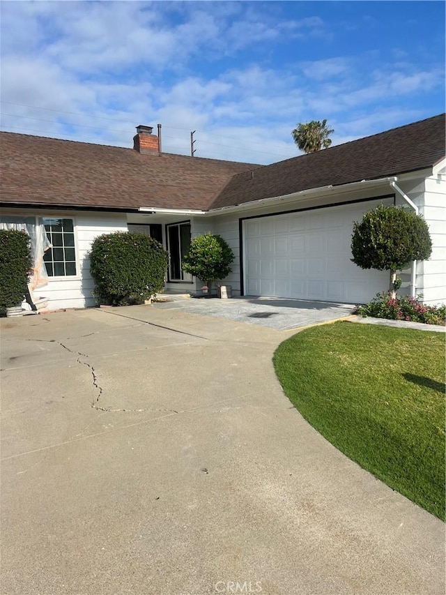 ranch-style home with a garage, driveway, and a chimney