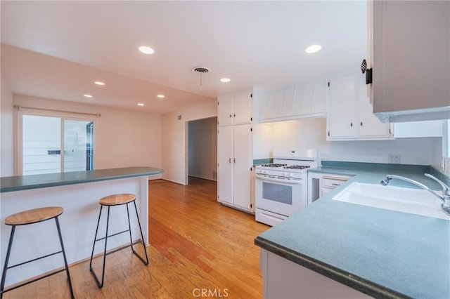 21122 Amberwick Ln, Huntington Beach, CA 92646 - kitchen with a breakfast bar, a sink, white range with gas cooktop, white cabinets, and light wood-type flooring
