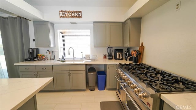 kitchen featuring range with two ovens, gray cabinetry, and a sink