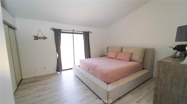 bedroom with baseboards, light wood-style flooring, and lofted ceiling
