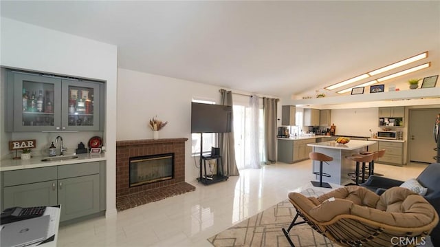 living area featuring light tile patterned floors, indoor wet bar, vaulted ceiling, and a brick fireplace