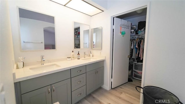 full bath with double vanity, a spacious closet, a sink, and wood finished floors