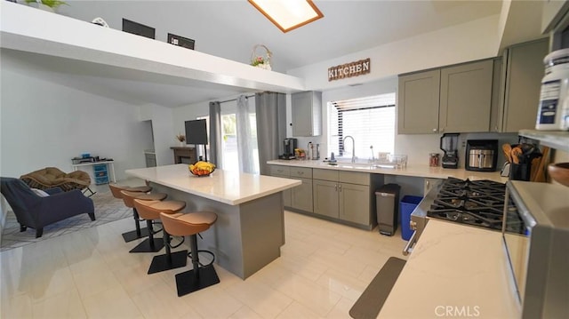 kitchen with a breakfast bar, light countertops, open floor plan, a kitchen island, and gray cabinetry
