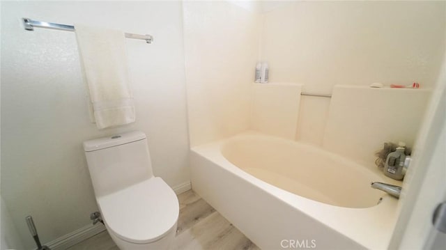bathroom featuring toilet, a tub, baseboards, wood finished floors, and a shower
