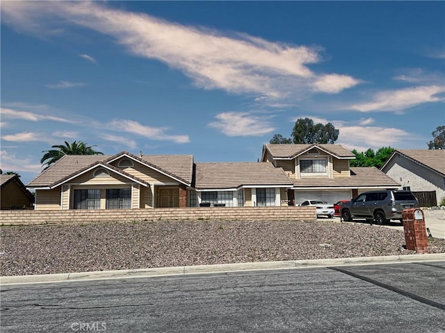 view of front of home with a garage, a tiled roof, and driveway