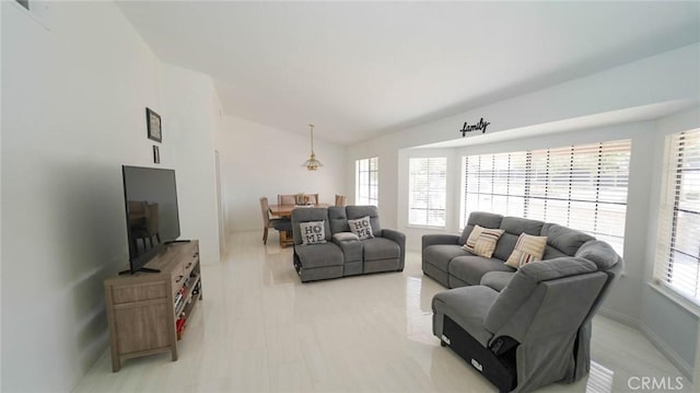 living area featuring baseboards and lofted ceiling