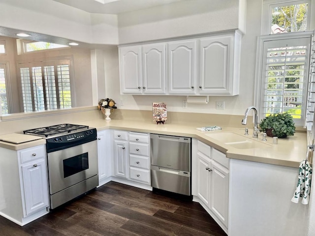 kitchen with white cabinets, dark wood-style flooring, appliances with stainless steel finishes, a sink, and a peninsula