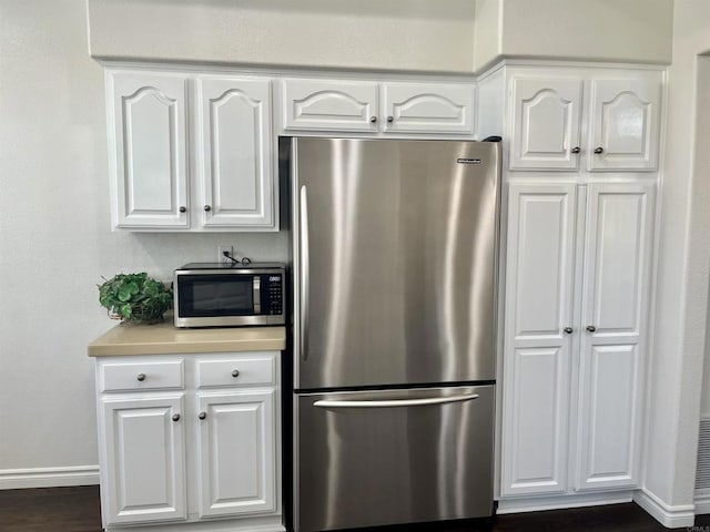 kitchen featuring light countertops, appliances with stainless steel finishes, baseboards, and white cabinetry