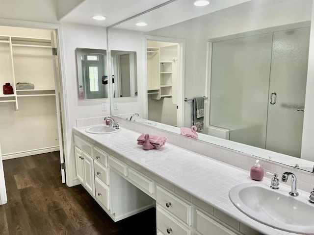 bathroom featuring a walk in closet, a stall shower, wood finished floors, vanity, and recessed lighting