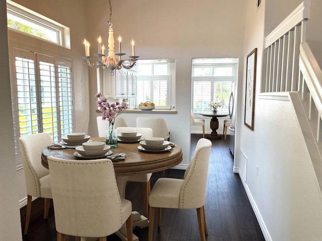 dining space with an inviting chandelier, baseboards, a high ceiling, and dark wood-style floors