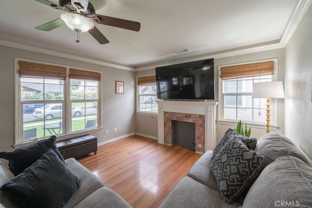 living area featuring baseboards, ornamental molding, ceiling fan, wood finished floors, and a tile fireplace