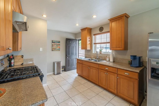 kitchen with a sink, extractor fan, brown cabinetry, recessed lighting, and stainless steel fridge