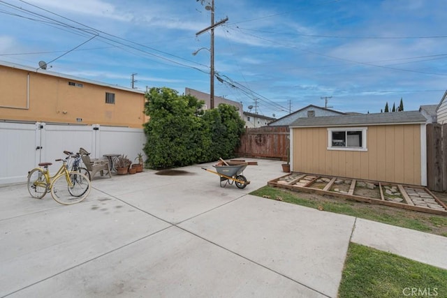 view of patio featuring a fenced backyard, an outdoor fire pit, and an outbuilding