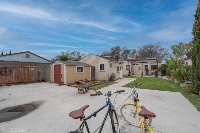 back of property with a patio area, an outdoor structure, fence, and a shed