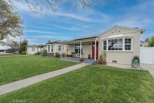 single story home featuring a front yard, a porch, solar panels, and fence