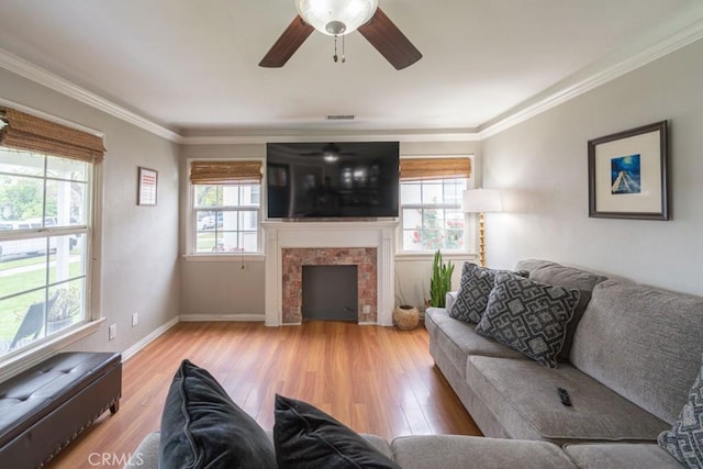 living room featuring ceiling fan, visible vents, a tiled fireplace, and wood finished floors