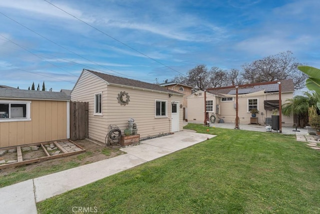 rear view of property featuring a yard, a patio, an outdoor structure, and fence