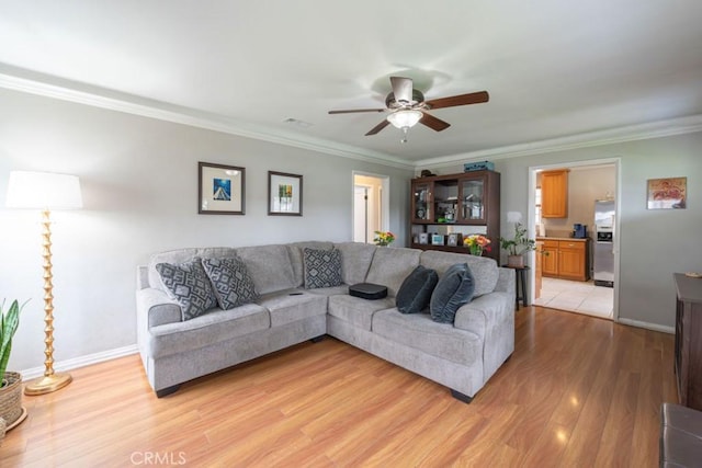 living room featuring a ceiling fan, baseboards, light wood-type flooring, and crown molding