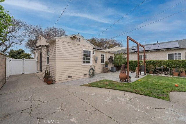 rear view of property with a patio, a gate, crawl space, fence, and a yard