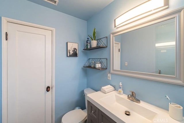 bathroom with toilet, vanity, and visible vents