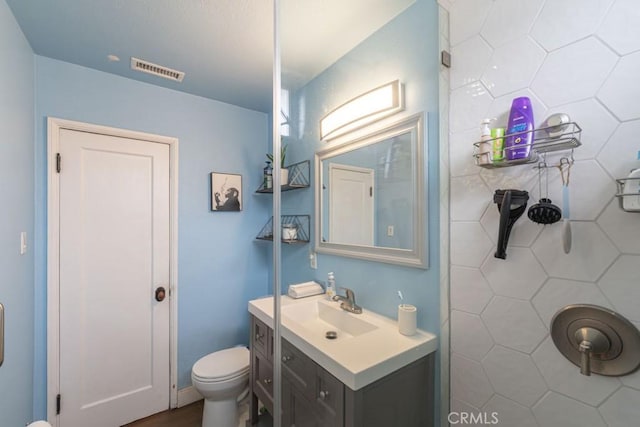 bathroom with toilet, visible vents, and vanity