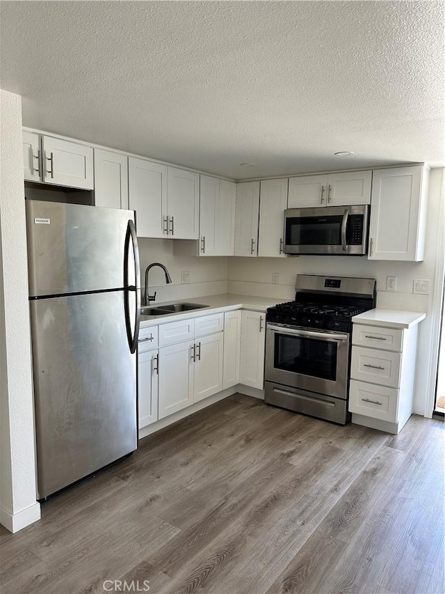 615 Calle Campana, San Clemente, CA 92673 - kitchen with a sink, appliances with stainless steel finishes, white cabinets, and light wood finished floors