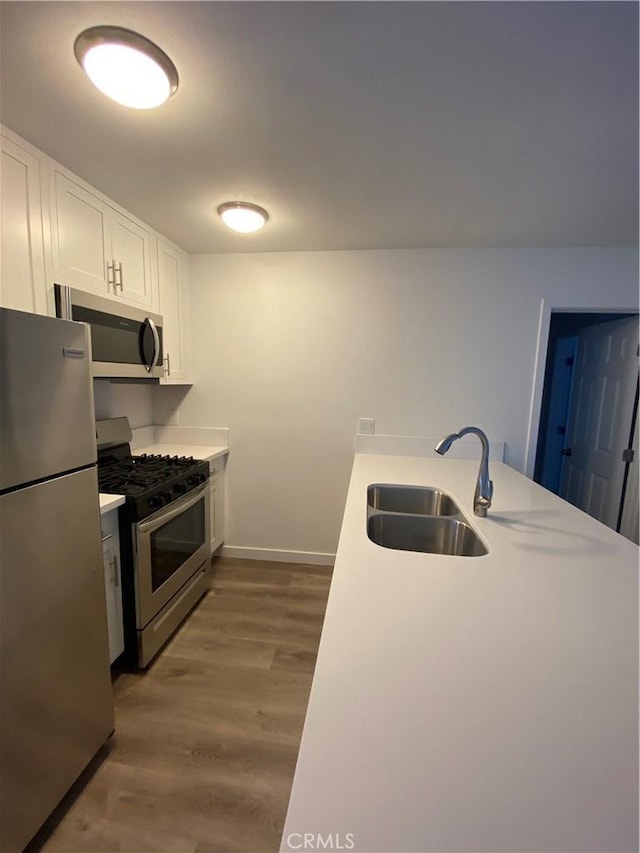 615 Calle Campana, San Clemente, CA 92673 - kitchen with appliances with stainless steel finishes, wood finished floors, a sink, baseboards, and white cabinetry