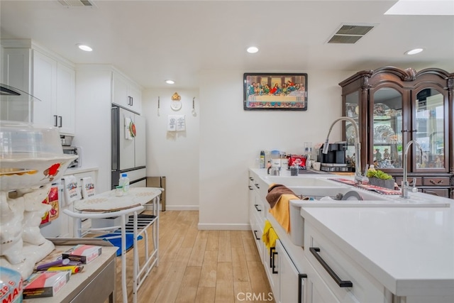 kitchen with visible vents, baseboards, light wood-style floors, recessed lighting, and white cabinetry