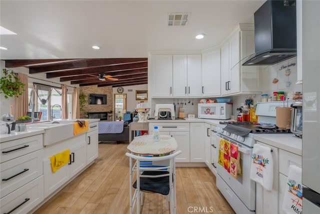 kitchen featuring a sink, beam ceiling, white appliances, wall chimney exhaust hood, and visible vents