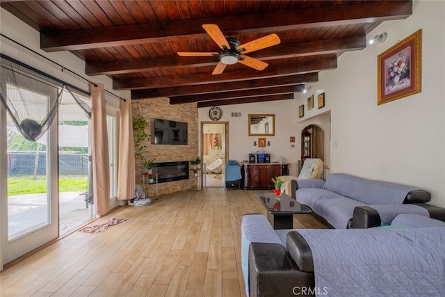 living area featuring plenty of natural light, wood ceiling, a stone fireplace, and light wood-type flooring