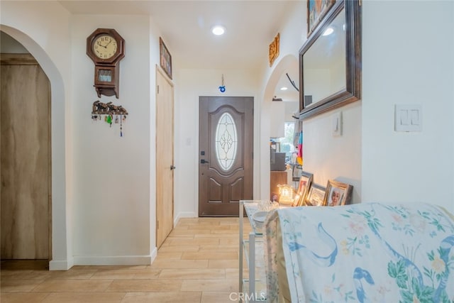 entryway featuring recessed lighting, arched walkways, baseboards, and light wood-type flooring