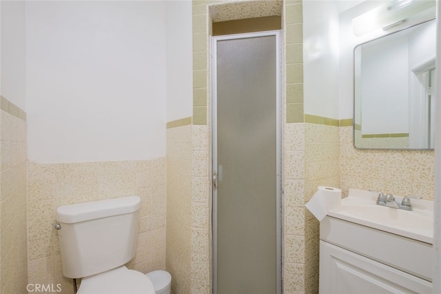 full bathroom with vanity, a shower stall, toilet, and tile walls