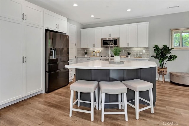 137 Lavender, Lake Forest, CA 92630 - kitchen with black fridge with ice dispenser, stainless steel microwave, white cabinets, and a breakfast bar