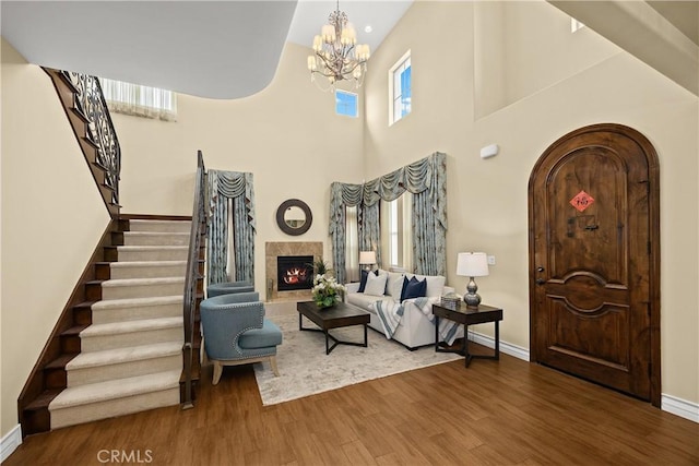 foyer entrance with an inviting chandelier, stairs, wood finished floors, arched walkways, and a premium fireplace