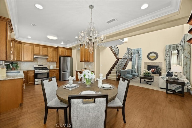 dining space with crown molding, stairs, wood finished floors, and a chandelier