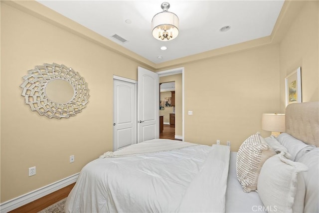 bedroom featuring a notable chandelier, recessed lighting, baseboards, wood finished floors, and visible vents