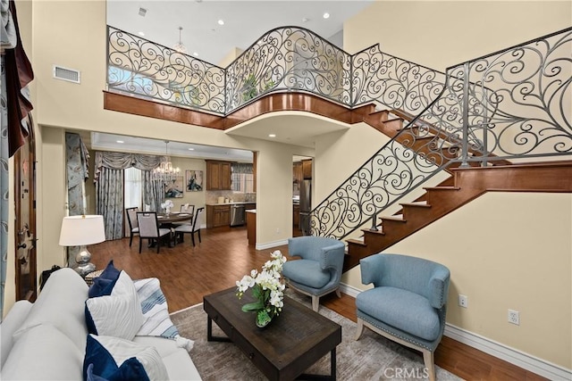 living room featuring stairs, dark wood finished floors, a chandelier, and visible vents